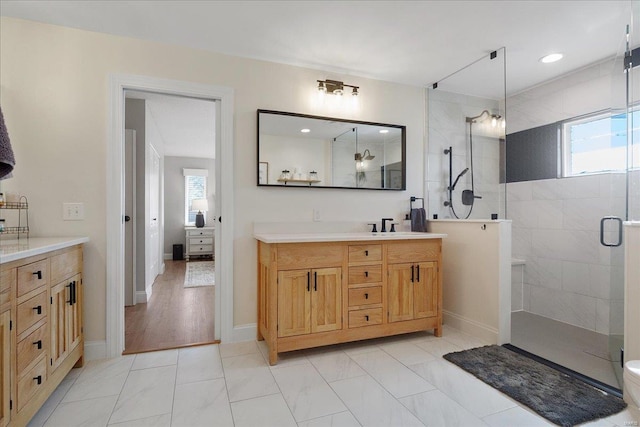 full bath with vanity, a walk in shower, and baseboards