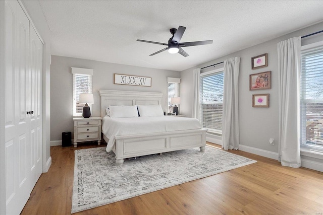 bedroom with baseboards, a textured ceiling, wood finished floors, and a ceiling fan