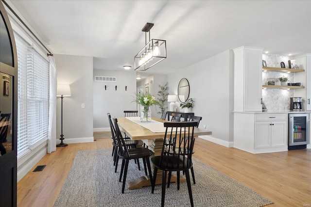 dining room featuring light wood-type flooring, visible vents, and wine cooler