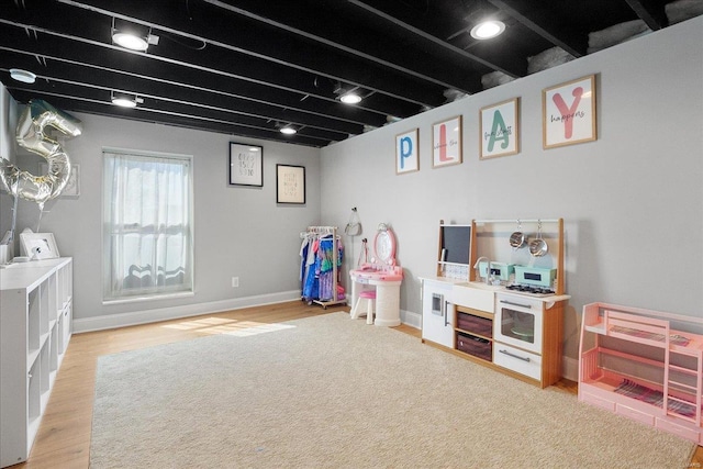 rec room featuring a sink, baseboards, and wood finished floors