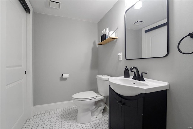 half bathroom with vanity, toilet, baseboards, and visible vents