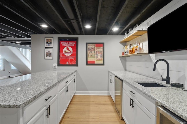 kitchen with beverage cooler, light wood-style flooring, a sink, open shelves, and a peninsula