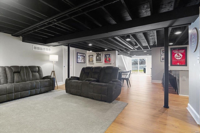 living room featuring visible vents, beamed ceiling, baseboards, and light wood-style floors