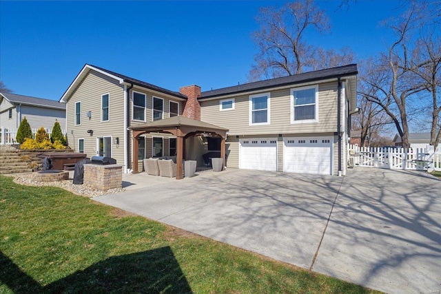 rear view of property featuring fence, a gazebo, driveway, area for grilling, and an attached garage