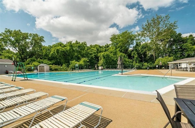 pool featuring a storage shed, a patio, and an outbuilding