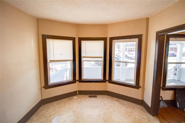 empty room with visible vents, baseboards, and a textured ceiling