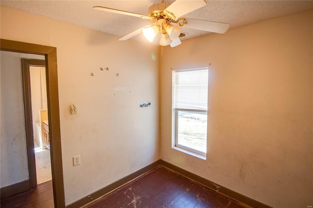 unfurnished room with dark wood finished floors, ceiling fan, baseboards, and a textured ceiling