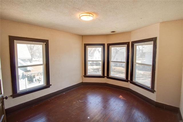 empty room with plenty of natural light, baseboards, and dark wood-style flooring