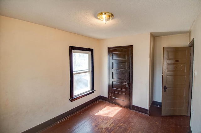 unfurnished bedroom with dark wood-type flooring, baseboards, and a textured ceiling