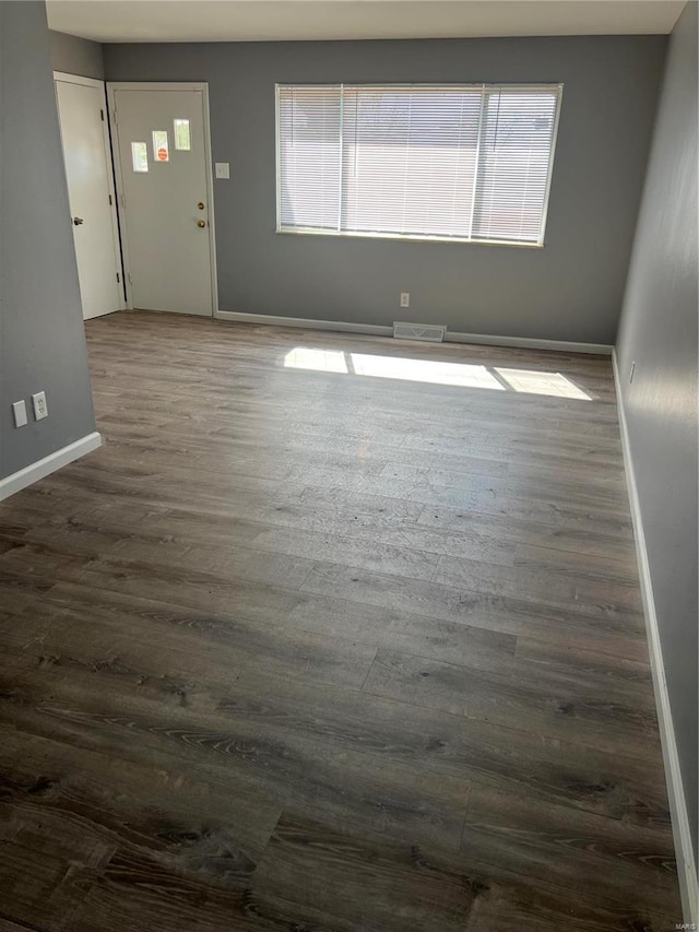 spare room with visible vents, baseboards, and dark wood-style flooring