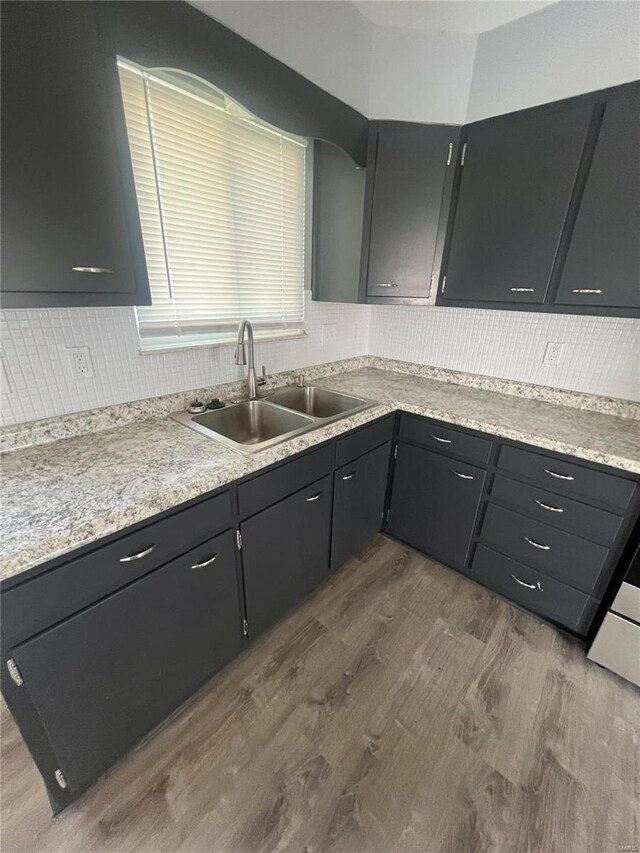 kitchen with decorative backsplash, light countertops, dark wood-type flooring, and a sink