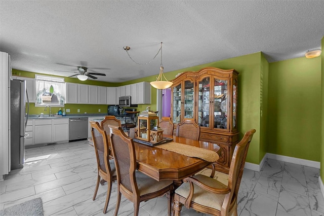 dining space with a textured ceiling, baseboards, marble finish floor, and ceiling fan