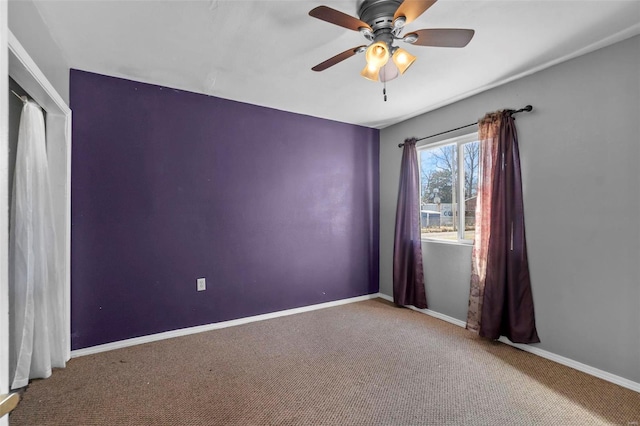 carpeted spare room featuring baseboards and ceiling fan