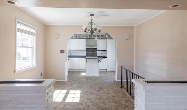 kitchen featuring dark countertops, decorative backsplash, white cabinetry, and crown molding