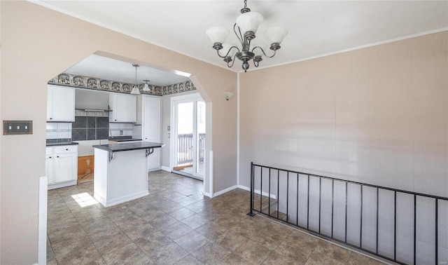 kitchen featuring a notable chandelier, decorative light fixtures, dark countertops, arched walkways, and white cabinets