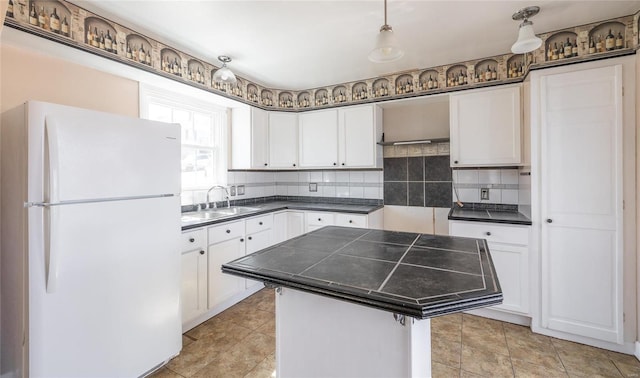 kitchen featuring a sink, backsplash, a center island, white cabinetry, and freestanding refrigerator