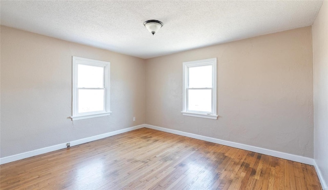 unfurnished room featuring a wealth of natural light, baseboards, and wood finished floors