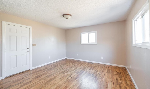 empty room featuring light wood finished floors, baseboards, and a wealth of natural light