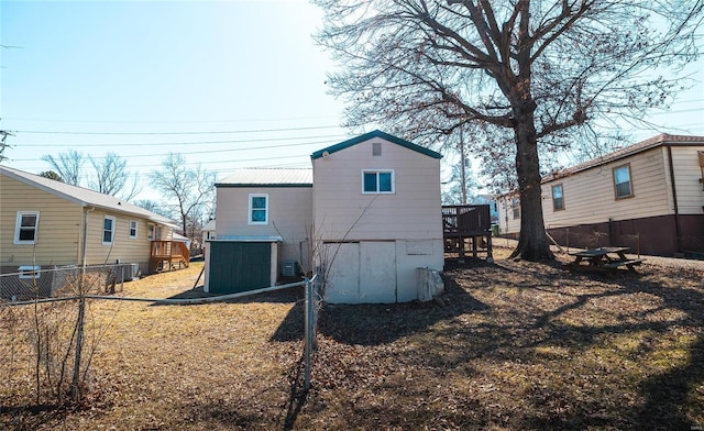 rear view of property featuring a deck, fence, and metal roof