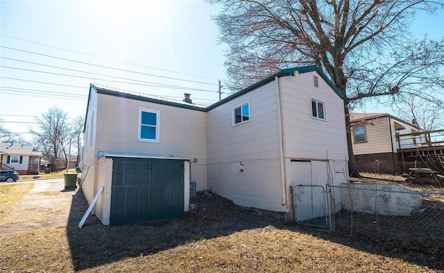 back of house with driveway, metal roof, and an attached garage