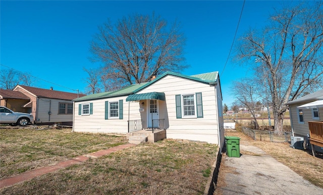 bungalow-style house with metal roof, a front yard, and fence