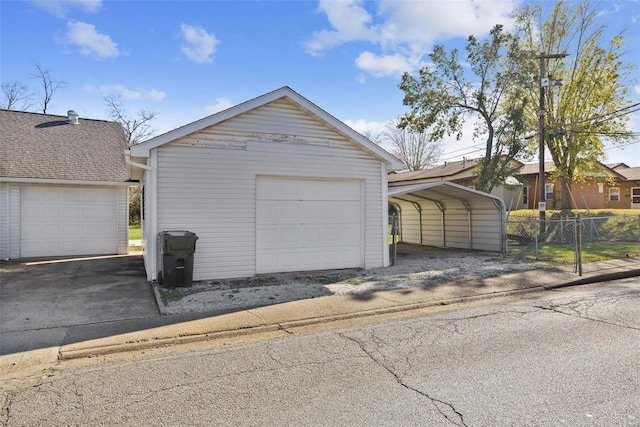 detached garage featuring a carport and fence