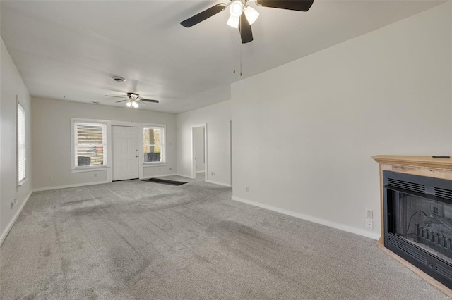 unfurnished living room with a ceiling fan, baseboards, carpet, and a fireplace