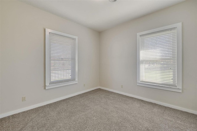 carpeted spare room featuring baseboards