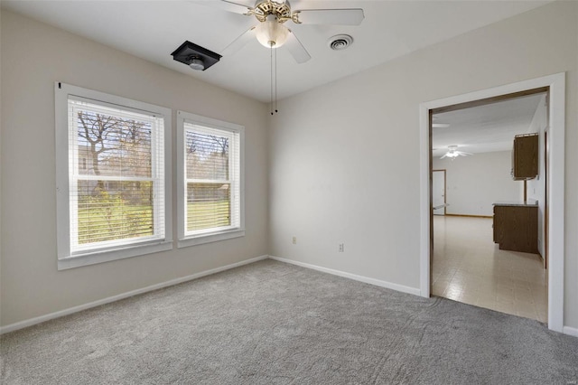 empty room with visible vents, baseboards, a ceiling fan, and carpet flooring