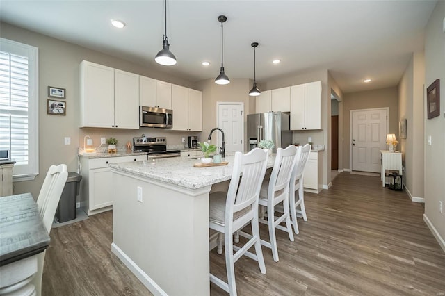 kitchen featuring white cabinets, wood finished floors, appliances with stainless steel finishes, and a sink