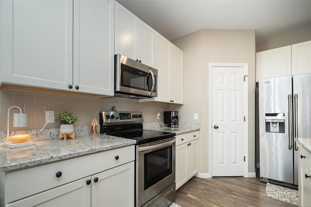 kitchen featuring backsplash, wood finished floors, white cabinetry, stainless steel appliances, and light stone countertops