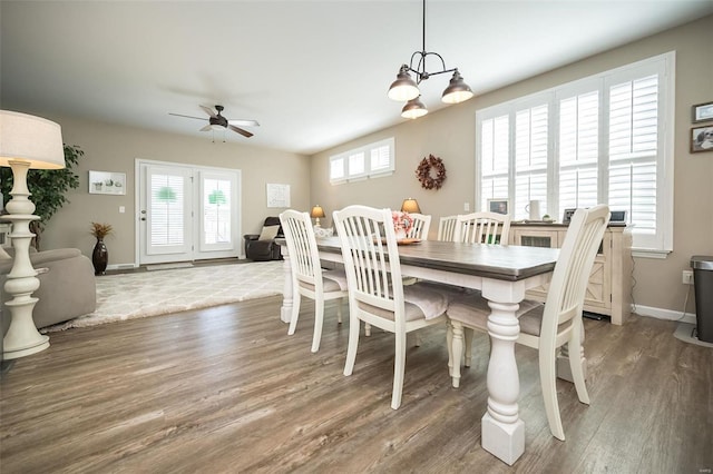 dining room with ceiling fan with notable chandelier, wood finished floors, baseboards, and a wealth of natural light