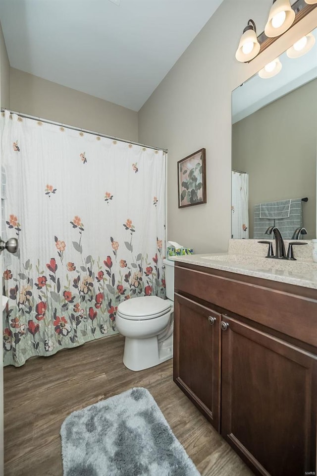 full bath featuring toilet, wood finished floors, and vanity