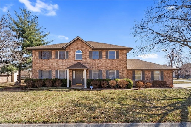 colonial house featuring brick siding and a front yard