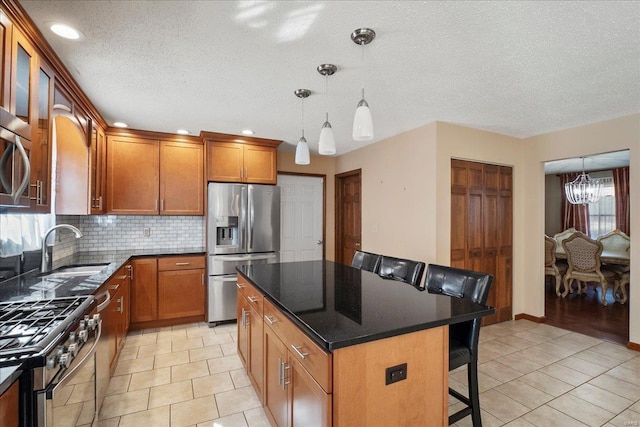 kitchen with brown cabinets, a sink, a kitchen breakfast bar, a kitchen island, and stainless steel appliances