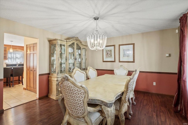 dining space featuring an inviting chandelier, wood finished floors, and a textured ceiling