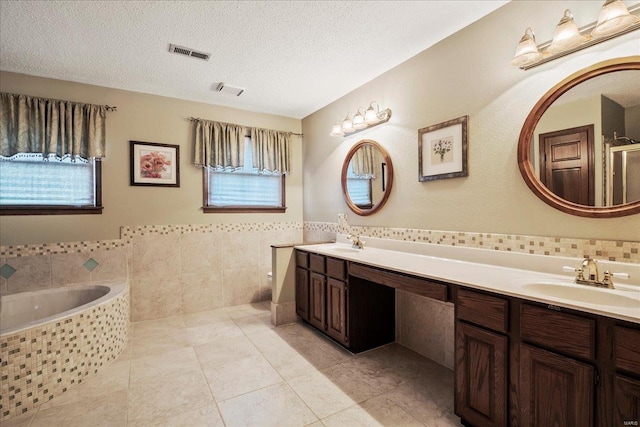 bathroom featuring visible vents, a textured ceiling, tile walls, and a sink