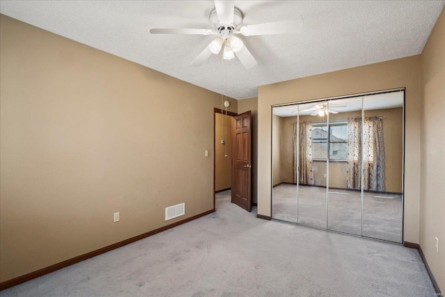 unfurnished bedroom featuring a ceiling fan, a textured ceiling, a closet, carpet, and baseboards