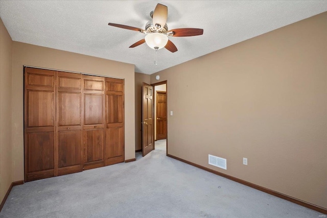 unfurnished bedroom featuring visible vents, baseboards, light carpet, a closet, and a textured ceiling