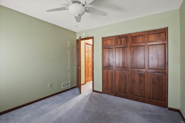 unfurnished bedroom with carpet, visible vents, baseboards, ceiling fan, and a textured ceiling