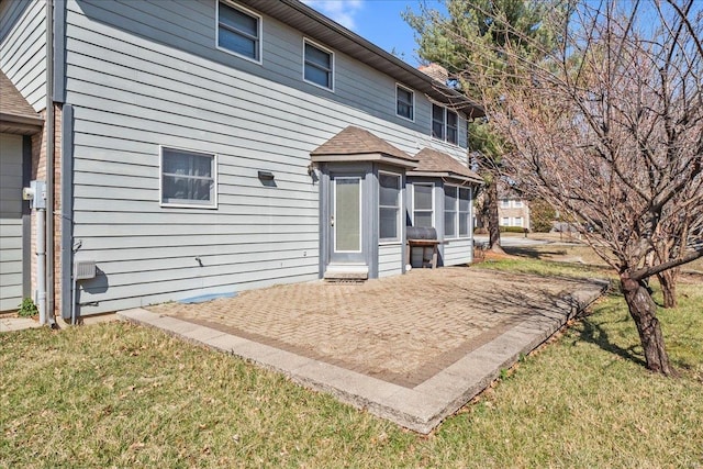 back of property featuring a patio area, a yard, and roof with shingles