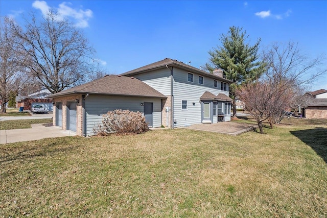 back of house featuring driveway, a yard, an attached garage, brick siding, and a chimney