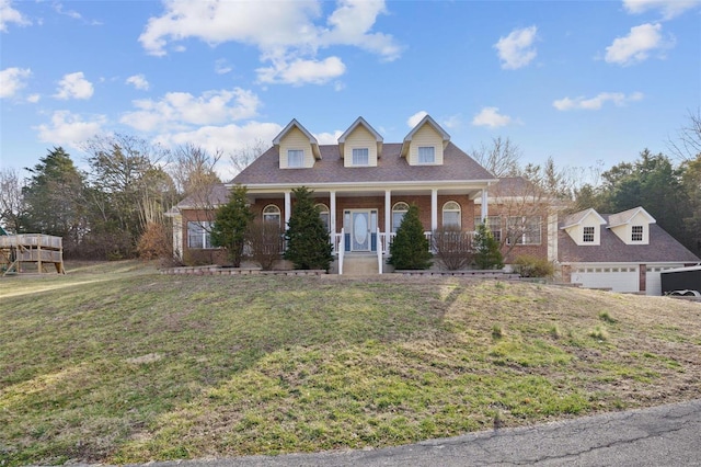 new england style home with a garage, brick siding, covered porch, and a front yard