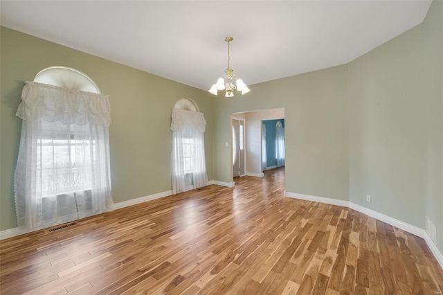 empty room featuring visible vents, baseboards, light wood-type flooring, and an inviting chandelier