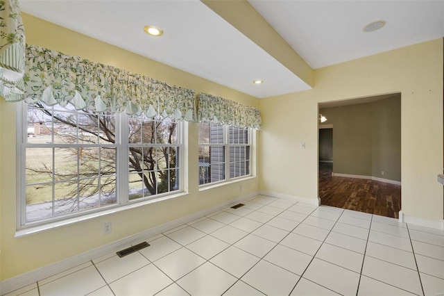 empty room with tile patterned flooring, visible vents, and a healthy amount of sunlight