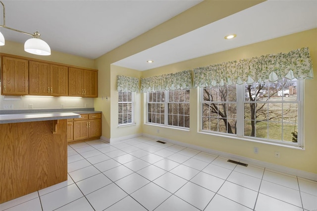 kitchen featuring brown cabinetry, visible vents, baseboards, and light tile patterned floors