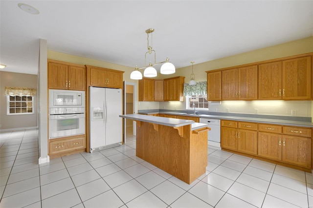 kitchen featuring white appliances, brown cabinets, a center island, and light countertops