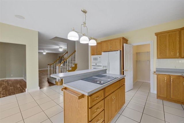 kitchen with white appliances, light tile patterned floors, hanging light fixtures, light countertops, and a center island