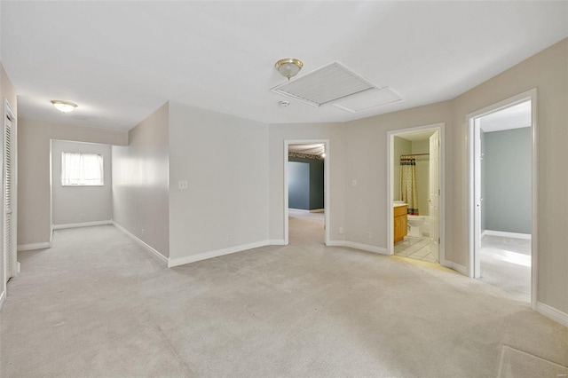 empty room featuring light colored carpet, attic access, and baseboards