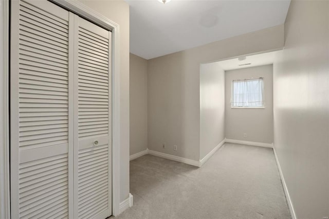 unfurnished bedroom with a closet, baseboards, and light colored carpet